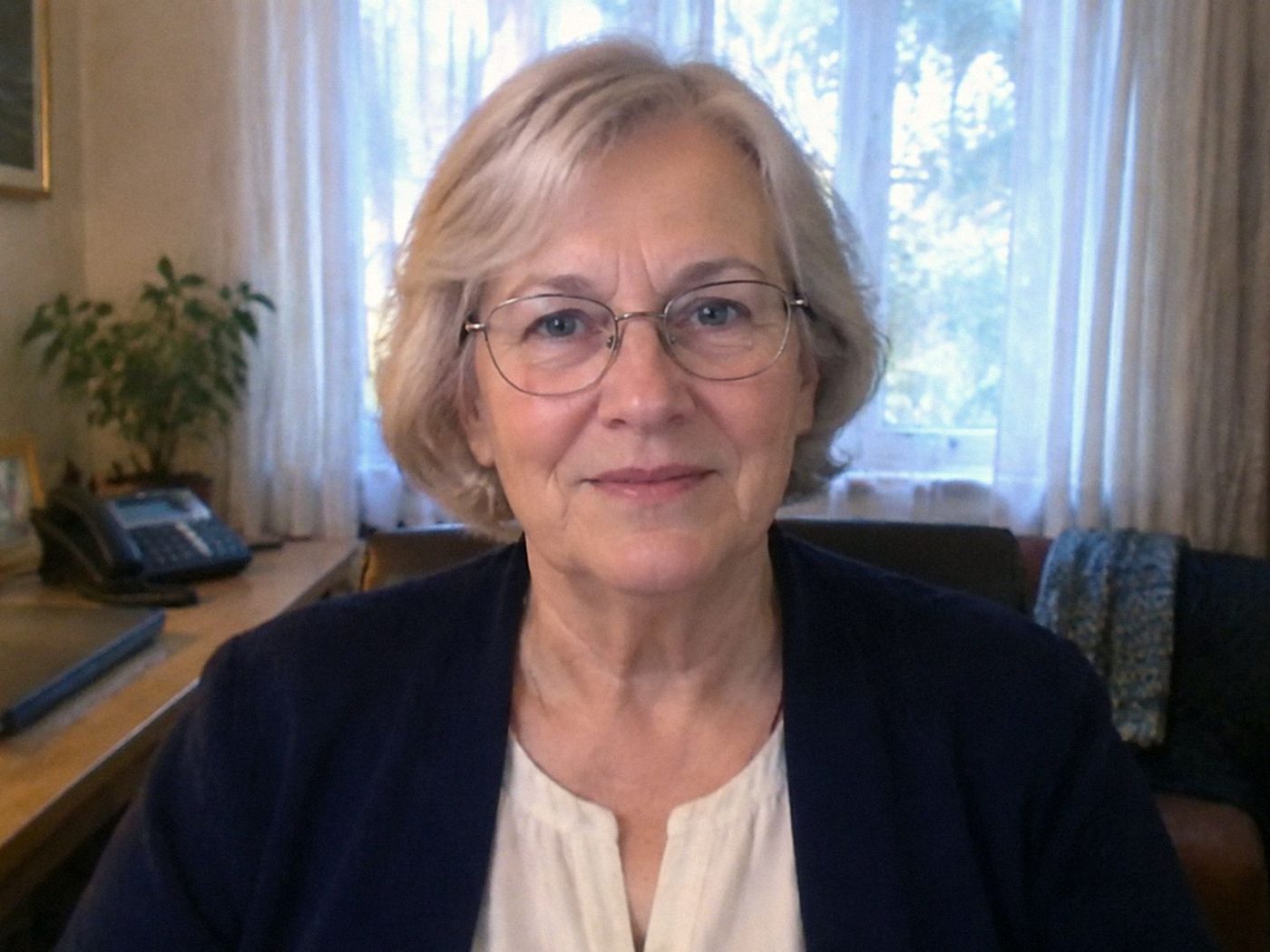Carol Jennings seated at her desk, case folders at the edge, a landline within reach